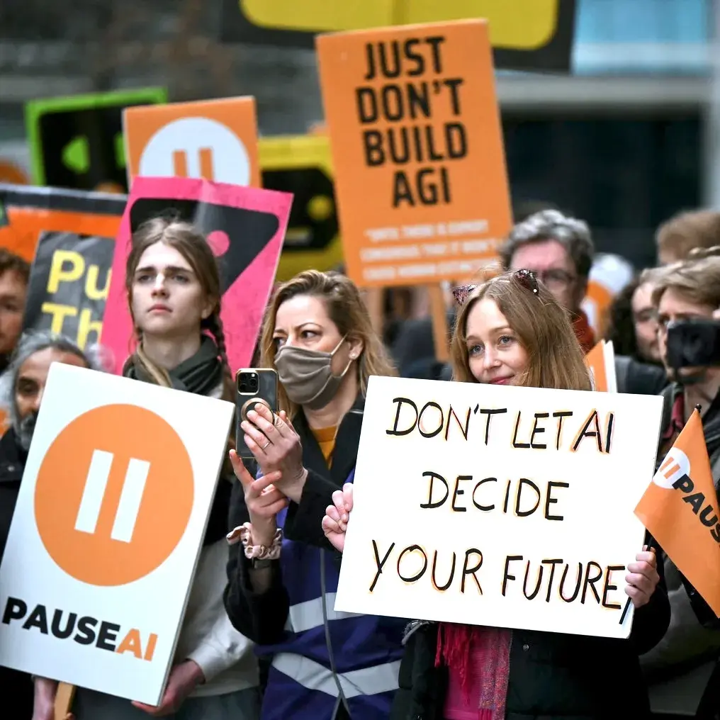 Marchers holding signs reading “Just don't build AGI” and “Don't let AI decide your future”